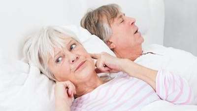 husband snoring while the wife holding her ear
