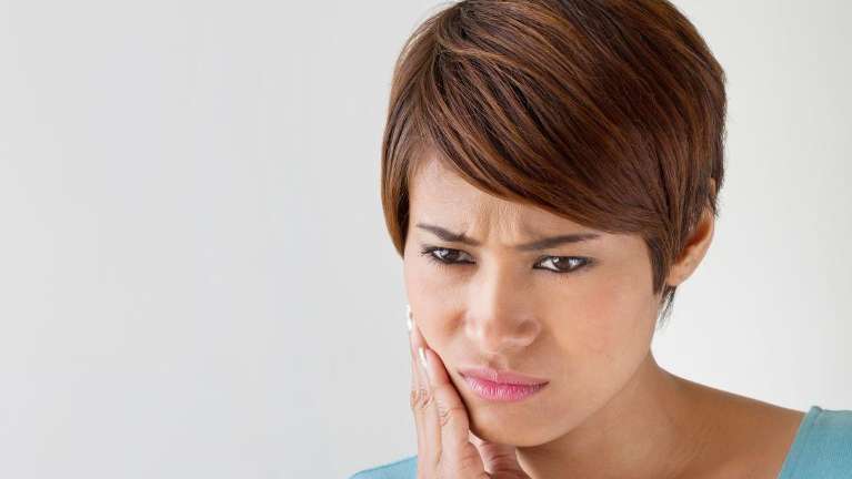 woman in pain holding her right cheek