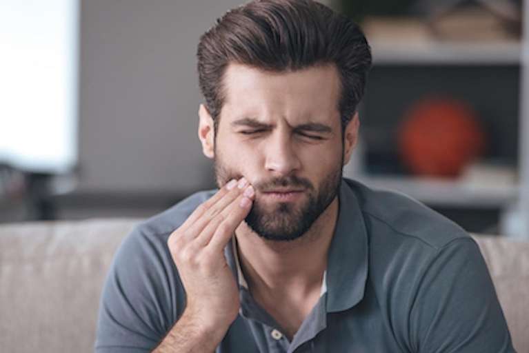 man in pain holding his right cheek